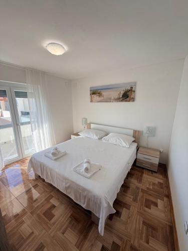 a white bedroom with a large bed with white sheets at Apartmani Lucija 3 in Zubovići