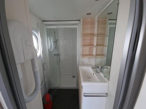 a white bathroom with a shower and a sink at Camping Les Goélands Carnac in Plouharnel