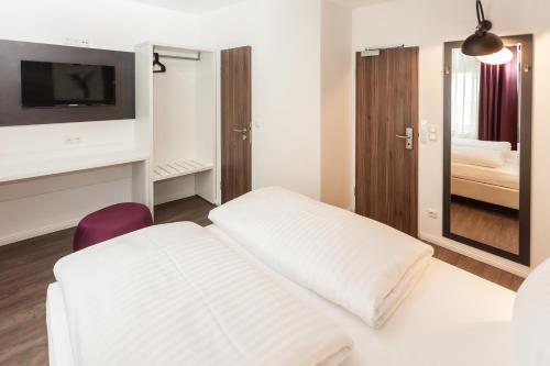 a hotel room with two white beds and a mirror at Hotel West in Hamburg