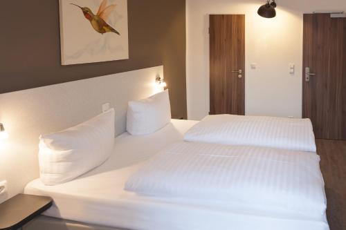 a white bed with white pillows in a bedroom at Hotel West in Hamburg