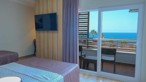 a hotel room with a bed and a balcony with a view at AZAK BLUE OTEL in Okurcalar