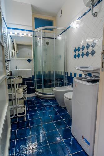 a bathroom with a glass shower and blue tiles at Acquarium dream apartment kate in Genoa
