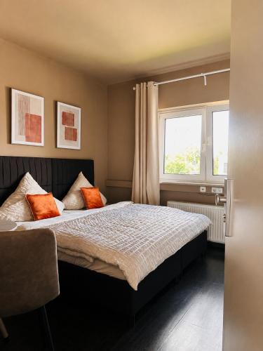 a bedroom with a bed with orange pillows and a window at BASE stay Erlangen in Erlangen