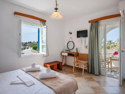 a bedroom with a bed and a desk and a window at Akteon Hotel in Logaras