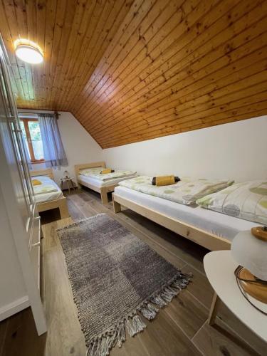 two beds in a room with a wooden ceiling at Chata Harmony in Ružomberok