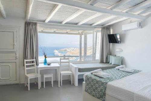 a bedroom with two beds and a table with a view at Eagles Nest Mykonos Suites & Apartments - Shared Pool & Jacuzzis in Mikonos