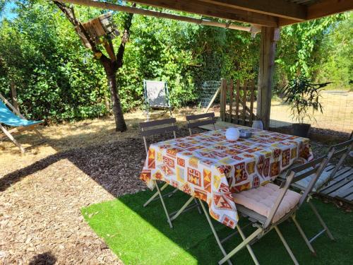 a table and chairs with a tablecloth on a patio at Maisonnette cosy au calme avec jardin clos - Puy dufou in La Ronde