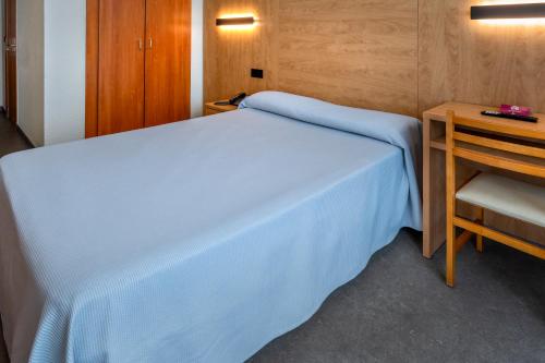 a small bedroom with a blue bed and a table at Hotel President in Calella