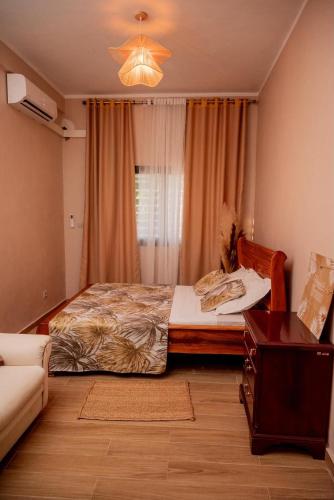 a bedroom with a bed and a couch and a table at Villa Royfa in Mahajanga