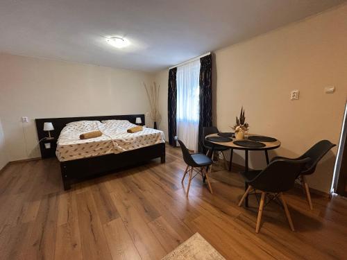 a bedroom with a bed and a table and chairs at Summer Apartments in Tiszakécske