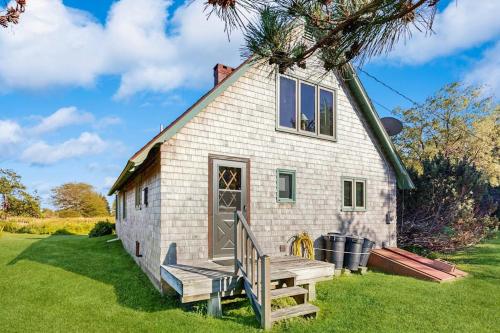 a small white house with a porch and a bench at Peaceful coastal cabin with screened porch, water view of the cove, dog-friendly in Owls Head