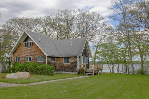 a brick house with a bench in a yard at Remodeled Waterfront Home with Wraparound Deck, Water Views, & Beach Access in Waldoboro