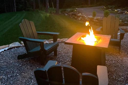 a fire pit with two chairs and a table with a fire burns at Amazing All-Season Sprucewold Cabin w/ Private Beach Club Access Dog-friendly in Boothbay Harbor