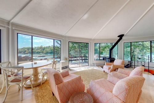 a living room with chairs and a table and windows at Unique oceanfront home with a deck, tons of natural light, & amazing views in Wiscasset