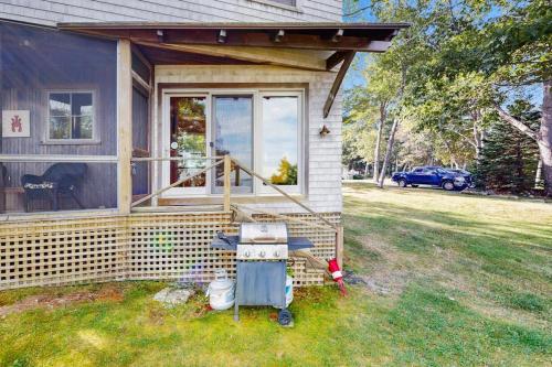 a house with a screened in porch and a yard at Waterfront Paradise with Dock, Big Yard, Sundeck & Epic Bay Views | Dog-Friendly in Boothbay