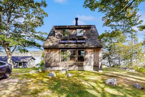 a stone house with a car parked in the yard at Waterfront Paradise with Dock, Big Yard, Sundeck & Epic Bay Views | Dog-Friendly in Boothbay