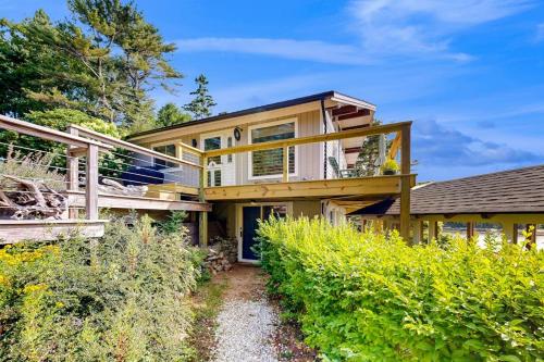 a large wooden house with a porch and a pathway at Stunning artist's retreat with ocean view & amazing deck, near Reid State Park in Georgetown