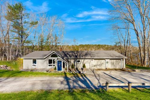 a white house with a blue door on a driveway at Gorgeous Waterfront Home on Westport Island with 2 Sunrooms in Montsweag