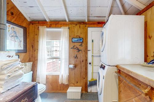 a kitchen with a white refrigerator and a window at Cozy, Waterfront Cabin-Style Gem with Private Dock and Lovely Views in East Harpswell