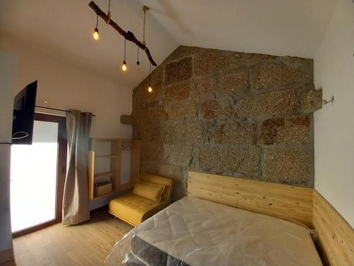 a bedroom with a stone wall with a bed and a chair at Quinta Pedra do Rio - Tâmega in Salvador do Monte