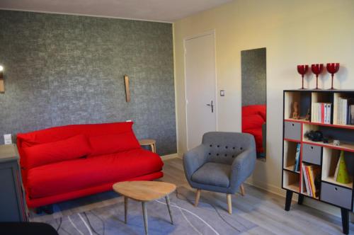a living room with a red couch and a chair at L'Escalère in Arnaud-Guilhem