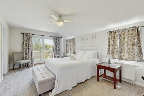 a white bedroom with a white bed and a window at Modern farmhouse with deck, firepit, & balcony in Northport