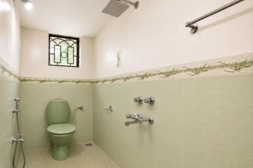 a bathroom with a green toilet and a window at Shiva Apartments & Stud!os GOA in Parra