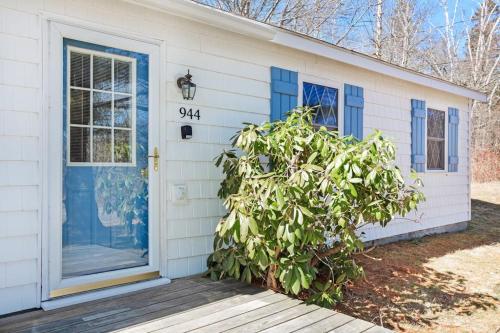 a white house with a blue door and a bush at Dog-friendly home in great locale close to the ocean with yard, streaming, W/D in Tremont