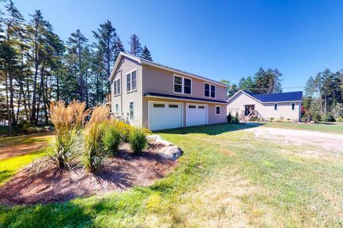 a house with a garage on a grass field at Newly-built waterfront home with fast WiFi, furnished deck, & washer/dryer in Waldoboro