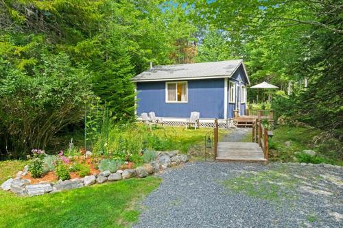 a blue tiny house in the middle of a yard at Woodland Home near Long Pond w/ Spacious Living Area, Full Kitchen & Deck in Somesville