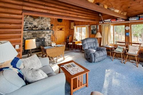 a living room filled with furniture and a stone fireplace at Vintage lakefront cabin with incredible water views, private dock & pebble beach in The Highlands