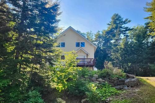 a white house in the middle of trees at Sunny coastal retreat with deck, grill, beach, dock, & ocean access in East Boothbay