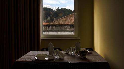 een tafel met stoelen en een tafel met een raam bij Ardínia the Legend in Lamego