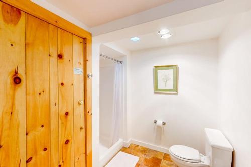 a bathroom with a white toilet and a wooden cabinet at Dog-friendly 3-story home with wood stove, deck, grill, ocean views, W/D, AC in Southwest Harbor
