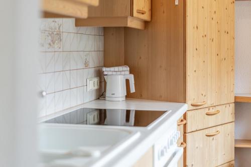 a kitchen with a white sink and wooden cabinets at Replers Hotel garni & Appartements in Prägraten
