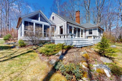 a white house with a chimney on top of a yard at Oceanfront retreat with sunrise views, screened porch, & deck in Blue Hill