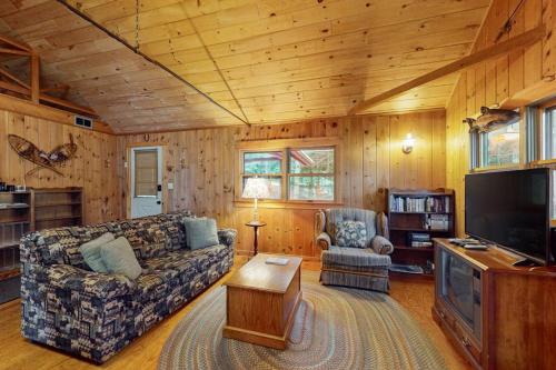 a living room with a couch and a tv at Lakefront Home with Private Dock, Pebble Beach & Enclosed Porch - Dogs Welcome in Greenville Junction