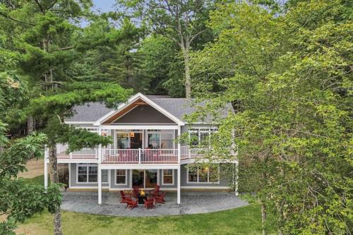 a large white house with a porch and patio at Elegant lakefront home near Bar Harbor & Acadia with modern kitchen, lake views in Orland