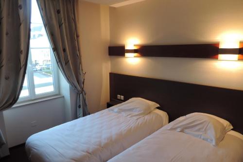 a hotel room with two beds and a window at Hôtel de France in Espalion