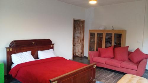a bedroom with a red bed and a red couch at Khalle Lodge in Dayr al Qamar