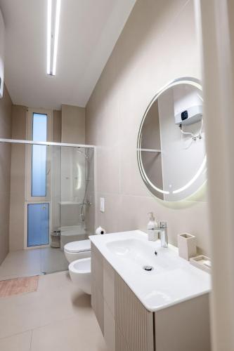 a bathroom with a sink and a toilet and a mirror at Kalpazo White Stones in Palasë