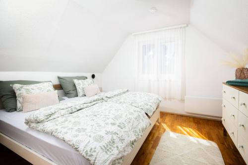 a white bedroom with a bed and a window at Fövenyes Hideaway in Balatonudvari
