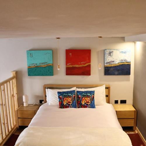 a bedroom with a white bed with paintings on the wall at The Tranquil Retreat Countryside Escape in Larkhall
