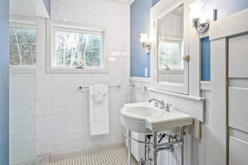 a white bathroom with a sink and a mirror at Waterfront Duplex, walkable, harbor views, AC, dog friendly in Camden