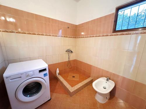 a bathroom with a washing machine and a toilet at Cozy Village Guesthouse in Delvinë