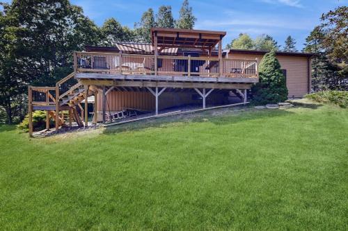a large house with a deck and a yard at Charming Lakefront House with Outdoor Firepit, Washer/Dryer and Wifi in Gouldsboro