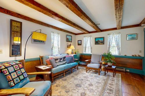 a living room with a blue couch and chairs and windows at Charming Seaside Cottage with a Gas Fireplace, Spacious Patio, and Nearby Hiking in Hancock