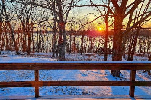 a bench in the snow with the sunset in the background at Spacious House with Modern Comforts and Nature in Cushing
