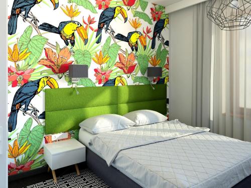 1 dormitorio con cabecero verde y papel pintado con motivos florales en Liv'Inn Aparthotel, en Cracovia