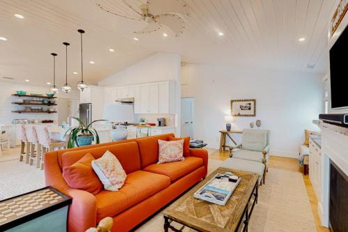 a living room with an orange couch and a kitchen at Perfectly Located Retreat with Grill, Fireplace, & Chef in Boothbay Harbor
